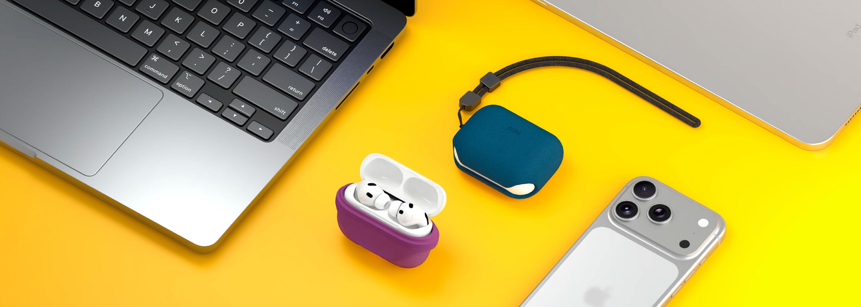 Dos AirPods Pro 3 con SiliconeGuard en colores magenta y azul naval sobre mesa amarilla, junto a iPhone 17 Pro Max plateado y MacBook